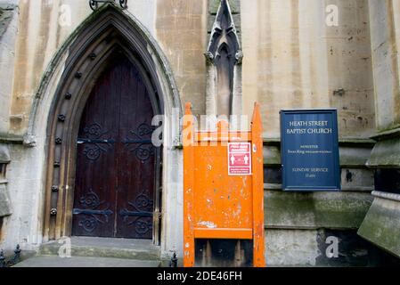 Heath Street Baptist Church entrance in Hampstead Village, London, with empty orange noticeboard only displaying social distancing  covid19 sign. Stock Photo
