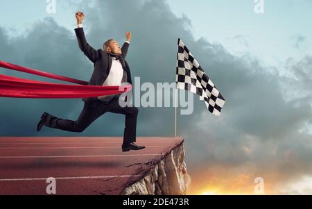 Businessman thinks she has won but there is a precipe after the finishline Stock Photo