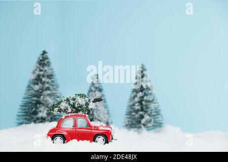 New Year red car with Christmas tree in snowy forest. Space for text. Happy New Year card concept Stock Photo