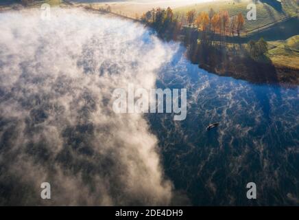Wafts of fog at the Irrsee with fishing boat, ground fog, from above, drone shot, aerial view, Salzkammergut, Upper Austria, Austria Stock Photo