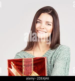 Young woman holding Christmas gift. Smiling female face Stock Photo