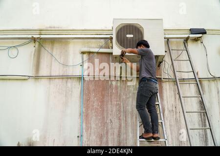 Air conditioner technician is installing the air conditioner on the wall of the house. Stock Photo