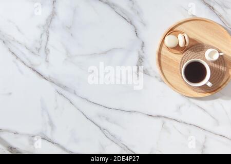 Flat lay composition of coffee, milk and macarons on wooden tray. Marble background Stock Photo