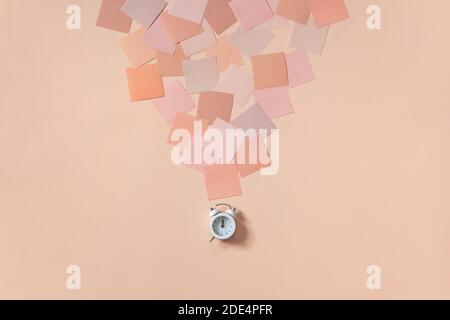 clock near stack of colorful notepads for writing goals and plans. Coral pink background Stock Photo