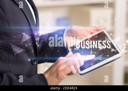Close up hands using tablet with BUSINESS inscription, modern business technology concept