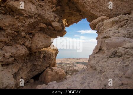 Hollow rock in Ein Gedi, in the background of the palm groves, the Dead Sea and Road No. 90. Israel. Stock Photo