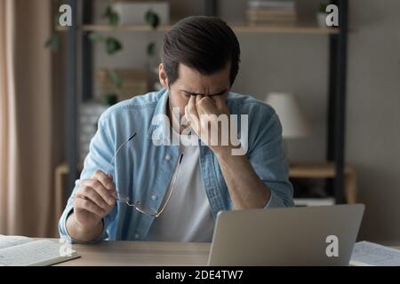 Unwell man take off glasses suffer from headache Stock Photo