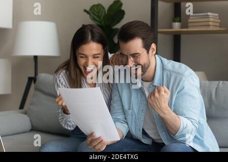 Excited couple triumph reading good news in letter Stock Photo