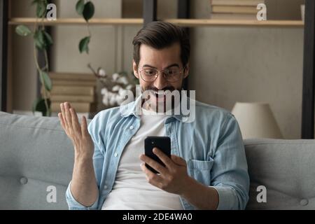 Amazed Caucasian man shocked by news on smartphone Stock Photo