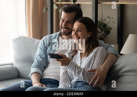 Smiling young couple relax on sofa watching TV Stock Photo