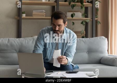 Young Caucasian man manage household finances using laptop Stock Photo