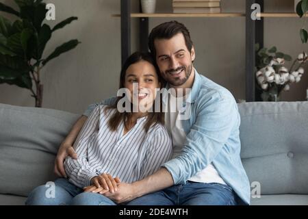Happy couple relax on sofa at home dreaming Stock Photo