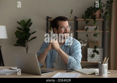 Smiling young man dream distracted from computer work Stock Photo