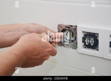 An electrican is repairing and installing a socket, outlet plug and switch. Stock Photo