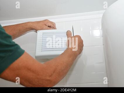 Bath fan repair, installation. Handyman installing new bath vent fan, ventilation system in the house bathroom. Stock Photo
