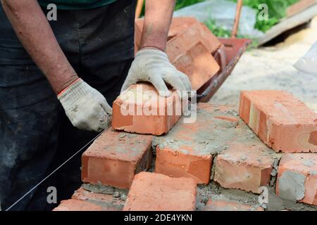 Bricklayer laying bricks. Bricklaying,  Masonry, Brickwork on new house wall construction site Stock Photo