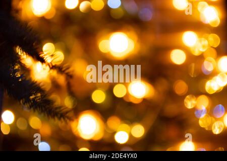 Abstract background yellow bokeh lights and branches of a tree in winter, Christmas background, cozy and warm feelings Stock Photo