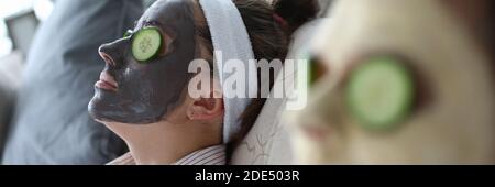 People are lying on couch with cosmetic mask faces Stock Photo