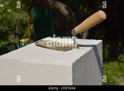 Metal trowel with wooden handle on the aerated concrete block Stock Photo