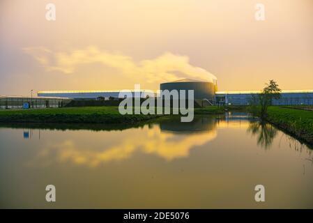 Greenhouses are heated on a cold evening in late autumn. Clouds are coloring light orange to pink due to the illumination of the greenhouses. Stock Photo