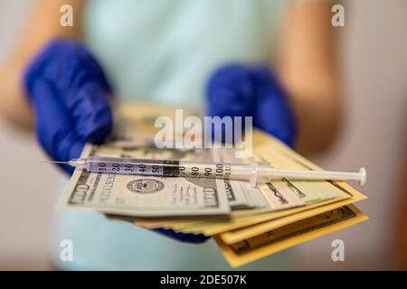 hands in medical gloves keep moneyon which the syringe lies. high quality Stock Photo