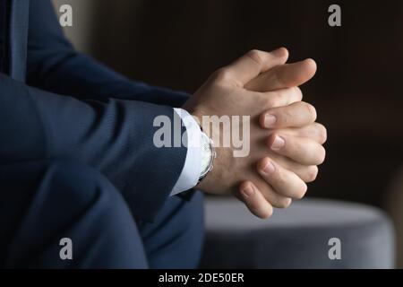Young businessman sitting with hands clasped keeping fingers in lock Stock Photo