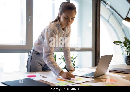 Thoughtful young businesswoman preparing accounting report in office using computer Stock Photo