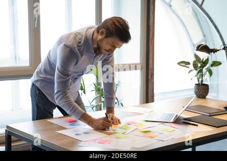 Thoughtful male employee correcting mistakes in marketing plan by hand Stock Photo