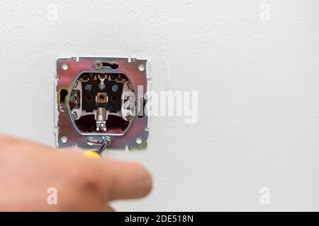 Wall mounting outlet using screwdriver, electrician hand close-up. Stock Photo