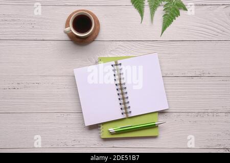 Open notepad with pen, coffee and green plants on wood table. Top view. Stock Photo