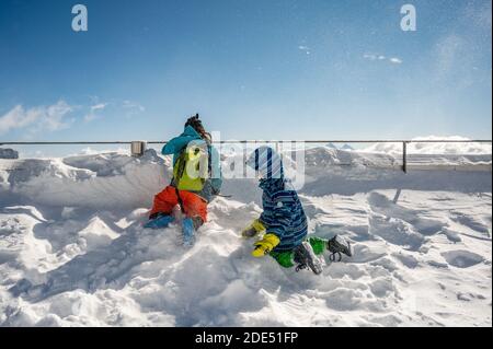 Back view of two kids playing with snow on the top of the mountain. Winter vacation with children in Alps. Glacier 3000, les Diablerets, Switzerland. Stock Photo