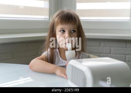 cute little girl uses nebulizer at home. treatment of bronchitis and asthma with inhalation Stock Photo