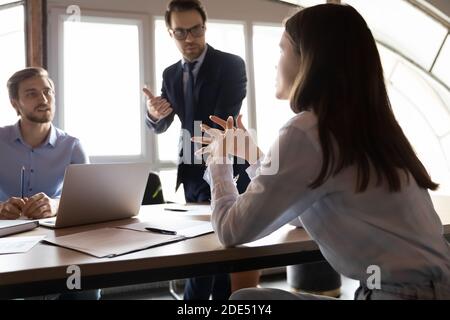Inspired female employee expressing idea to attentive male colleagues Stock Photo