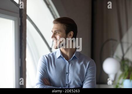 Successful young boss standing by window satisfied with career growth Stock Photo