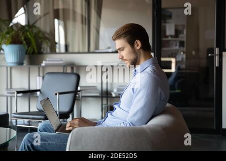 Confident businessman working with documents on laptop at modern office Stock Photo
