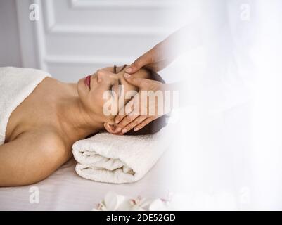 Beautiful brunette woman enjoying facial massage comfortable and bissfulle. Relaxing treatment in medicine and spa center concepts Stock Photo