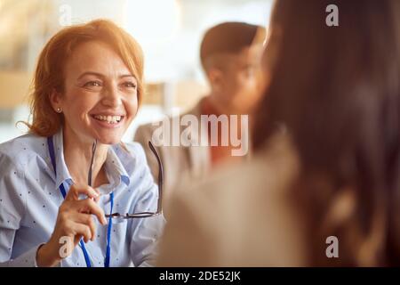 Young female colleagues having a pleasant talk in a cheerful atmosphere at a coffee break. People, job, company, business concept. Stock Photo