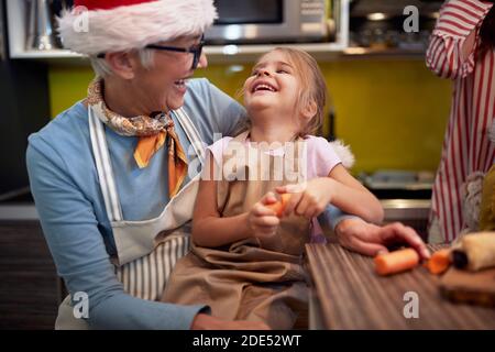 Happy grandma and granddaughter together in the kitchen in festive and cheerful christmas atmosphere. Christmas, family, together Stock Photo