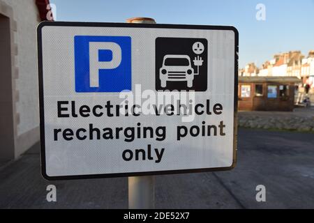 Isolated electric vehicle recharging point only sign in authentic location with parking icon and charging car icon. Scotland, UK.