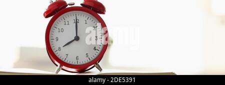 Red alarm clock standing on pale of books Stock Photo