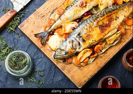 Delicious mackerel fish roasted with apples,served on kitchen board. Stock Photo