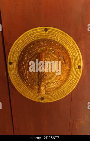 Golden Door Knocker On Red Wooden Dzong Door in Bhutan Stock Photo