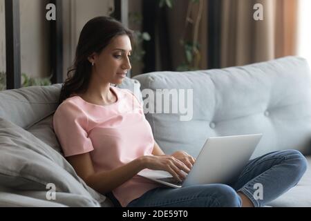 Happy millennial arabic indian woman working on computer at home. Stock Photo