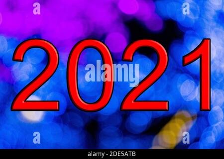 Red text with the number 2021 and embossed in black, with a background with a Bokeh effect, out of focus, in different colors and with blue and purple Stock Photo