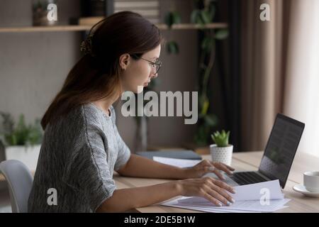Concentrated smart european businesswoman in eyeglasses working with documents. Stock Photo