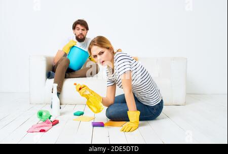 The man lies on the couch and the woman is cleaning the detergent on the floor Stock Photo