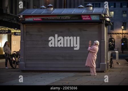 A lone shopper stops to take a photo on Oxford Street in London during the final weekend of Coronavirus Lockdown#2, London, England, UK Stock Photo