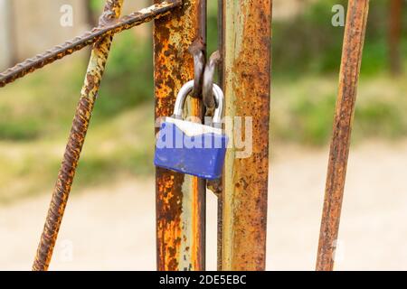 A padlock hangs on a rusty gate. Security concept, data protection, password and account hacking. Pick up the keys for the lock. Stock Photo