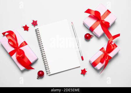 New Year goals List 2021 with white notebook written plan. Planning and setting goals for the next year. Christmas gift box wrapped in pink paper with red ribbon bow with copyspace Stock Photo
