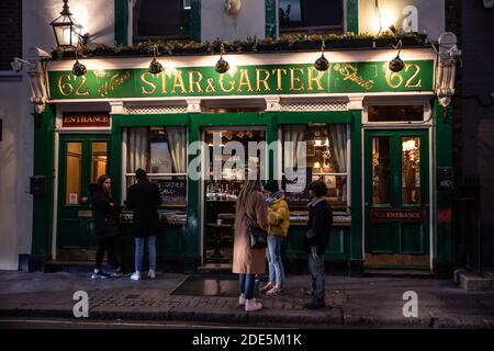 People stand outside The Star and Garter pub in Soho drinking take-away drinks during the coronavirus lockdown#2 restrictions, West End, London, UK Stock Photo